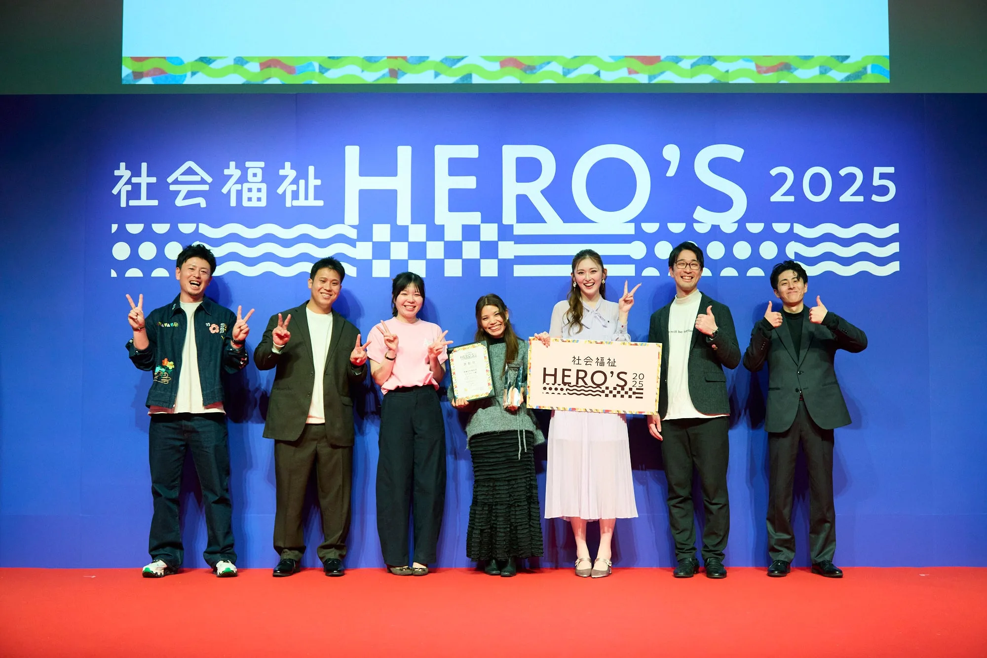 Lama Sabina with the other Social Welfare HERO'S 2025 finalists on stage, holding her trophy and award certificate.